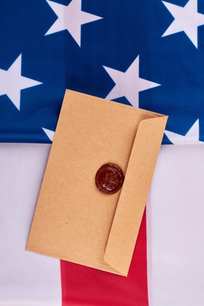 Envelope from craft paper on American flag. Background with flag of America and vintage style envelope with red wax seal stamp, top view.