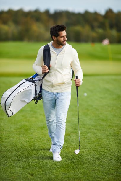 Young active man with golf club and bag looking for place where he can play