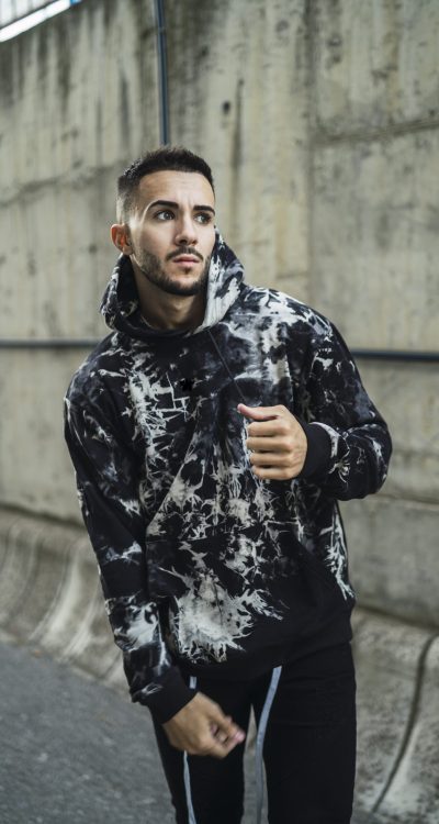 A vertical shot of a stylish young man wearing a hoodie